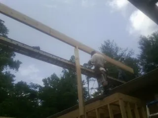 Carpenter setting a ridge beam over a new addition frame — Ice Dam Removal by Roofing Brothers in Earling