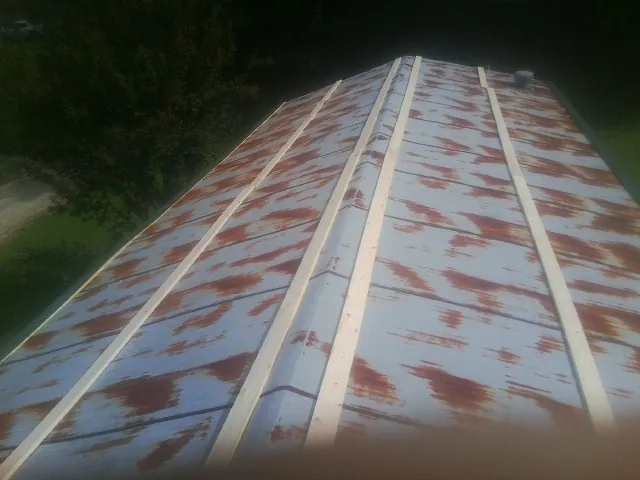 Rusted metal roof panels with new wood purlins before replacement — Storm Damage Roof Repair in Earling by Roofing Brothers