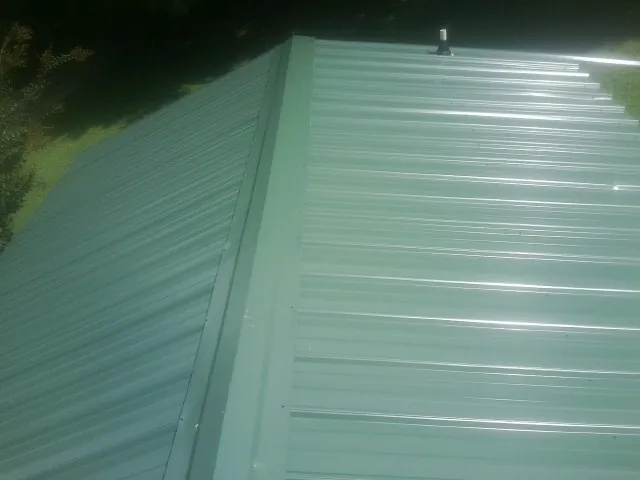 New green metal panels meeting at the ridge of a roof — Flat Roof Repair work by our crew in Earling