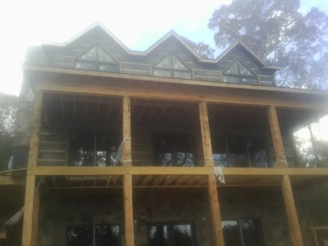 Dormers and porch framing on a large log home under construction — Roof Coating work by our crew in Earling