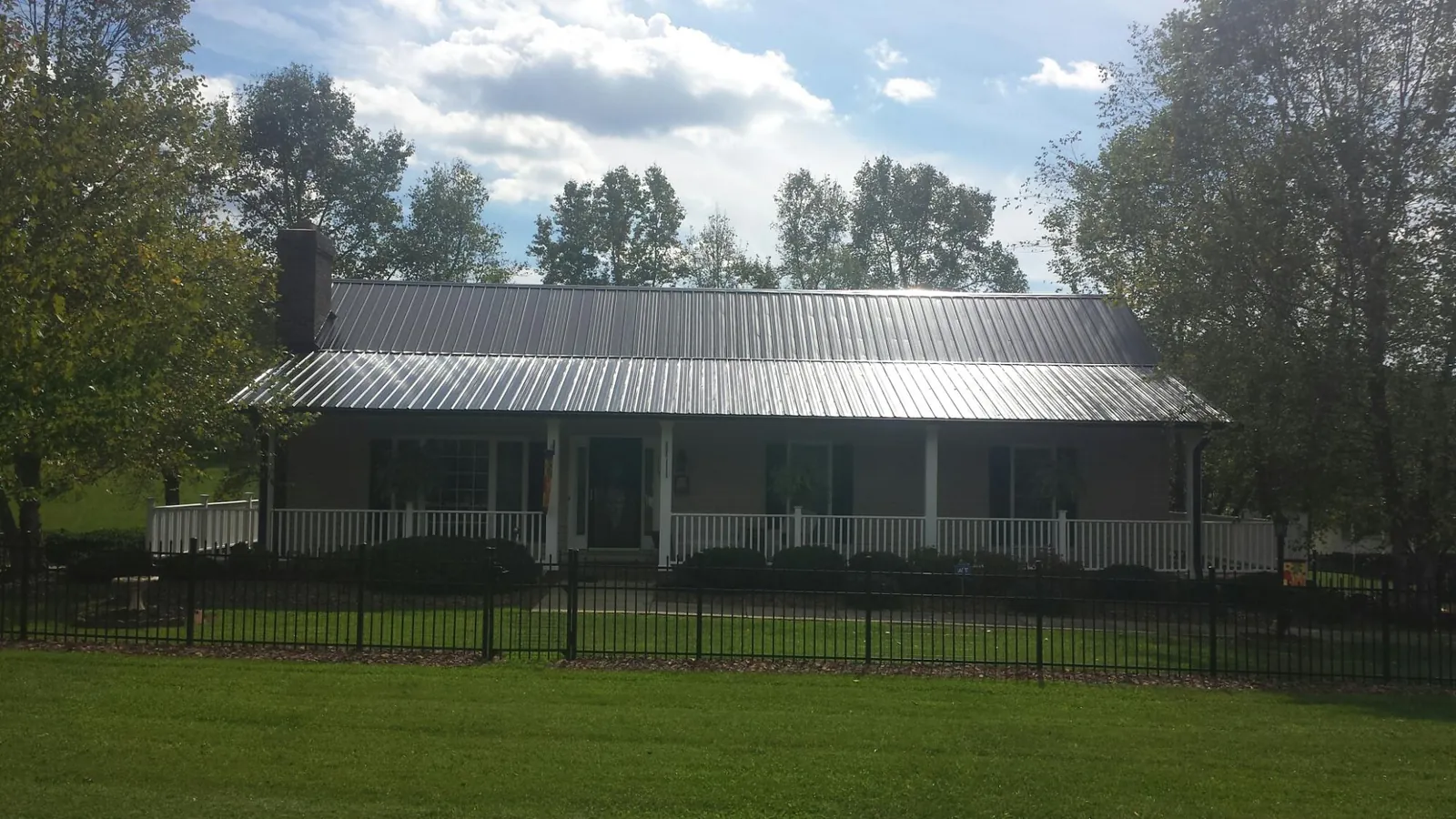 Gray metal roof on a brick ranch with a full width front porch — Gutter Guard Installation work by our crew in Earling