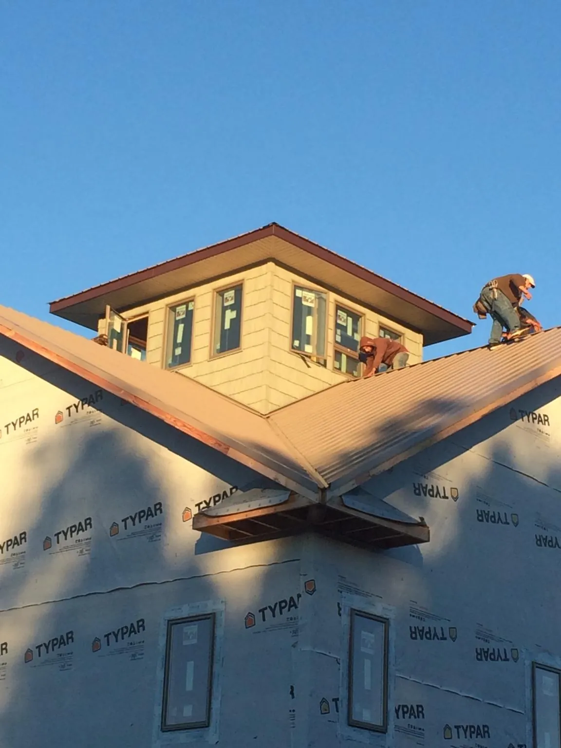 Roofers working around a rooftop cupola on a new metal roof at sunset — Roof Waterproofing in Earling by Roofing Brothers